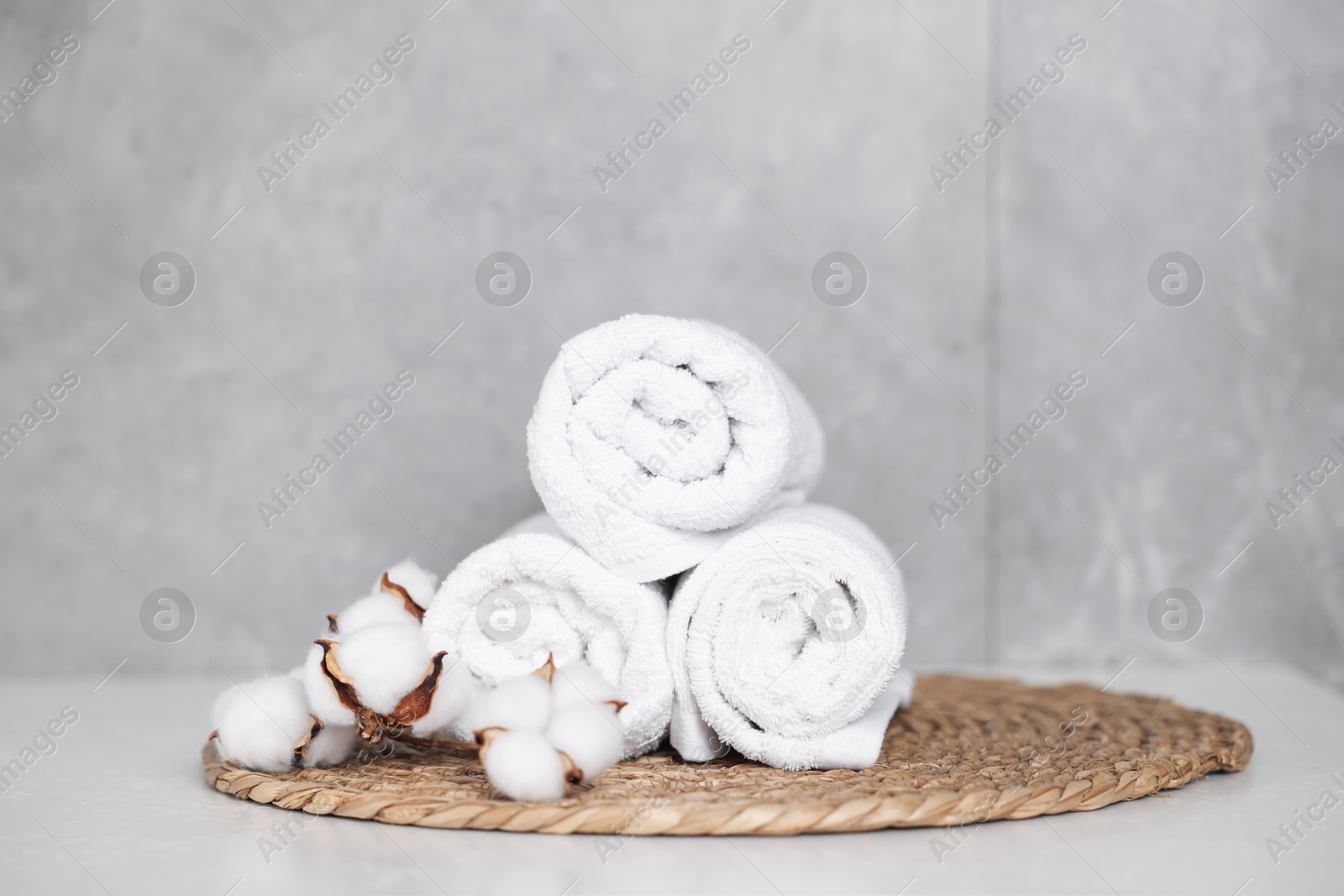 Clean towels and cotton flowers on white table indoors Photo of Clean towels and cotton flowers on white table indoors