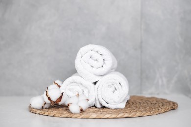 Photo of Clean towels and cotton flowers on white table indoors