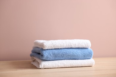 Photo of Stack of clean towels on wooden table against beige background