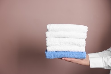 Photo of Woman with clean towels on beige background, closeup. Space for text