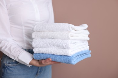 Photo of Woman with clean towels on beige background, closeup