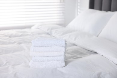 Photo of Clean terry towels on bed at home