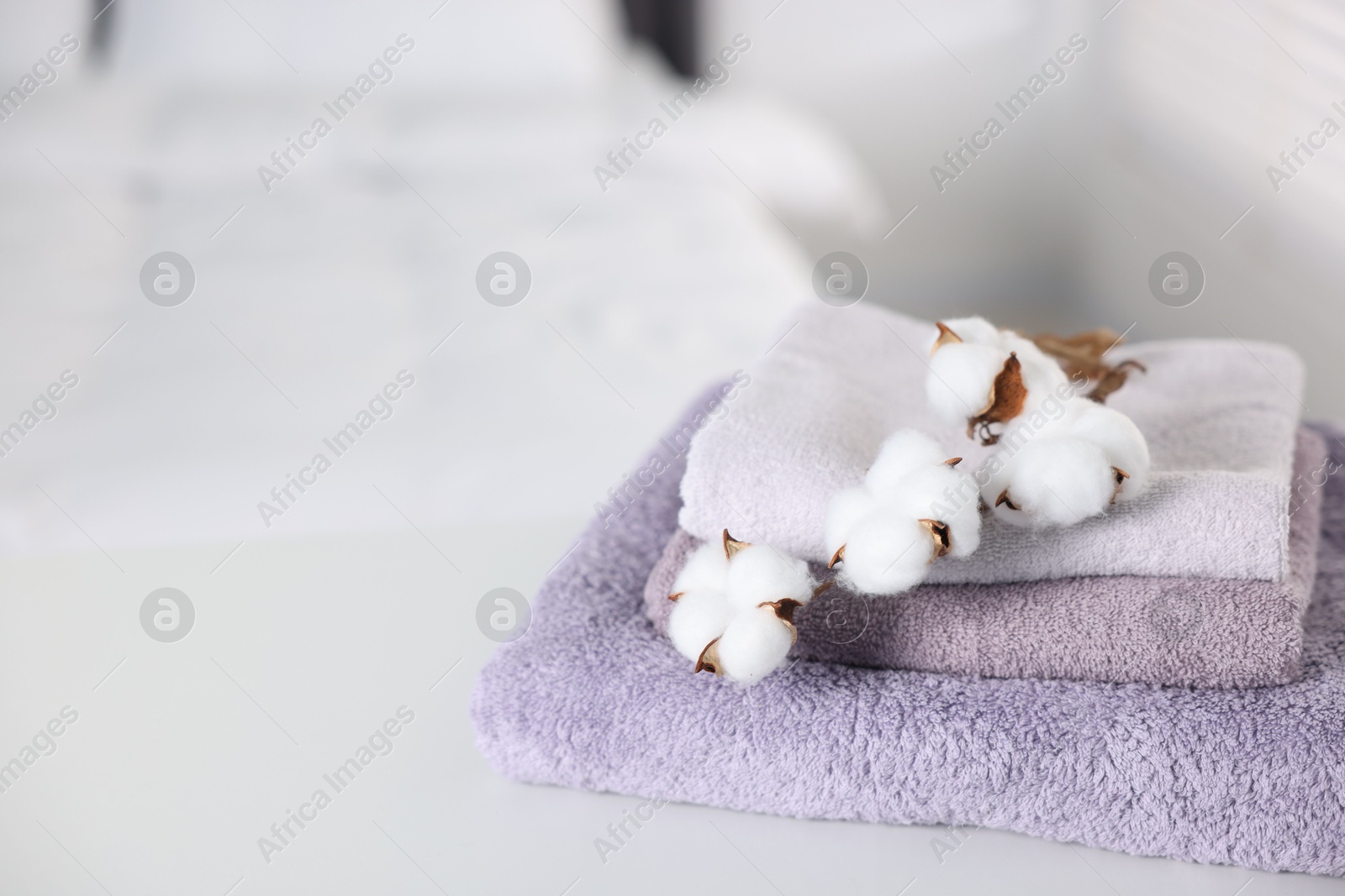 Clean terry towels and cotton flowers on bed at home, closeup. Space for text Photo of Clean terry towels and cotton flowers on bed at home, closeup. Space for text