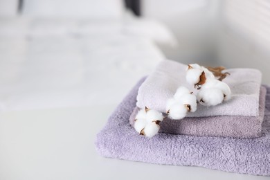 Photo of Clean terry towels and cotton flowers on bed at home, closeup. Space for text