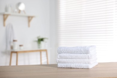 Photo of Clean terry towels on wooden table in bathroom, space for text