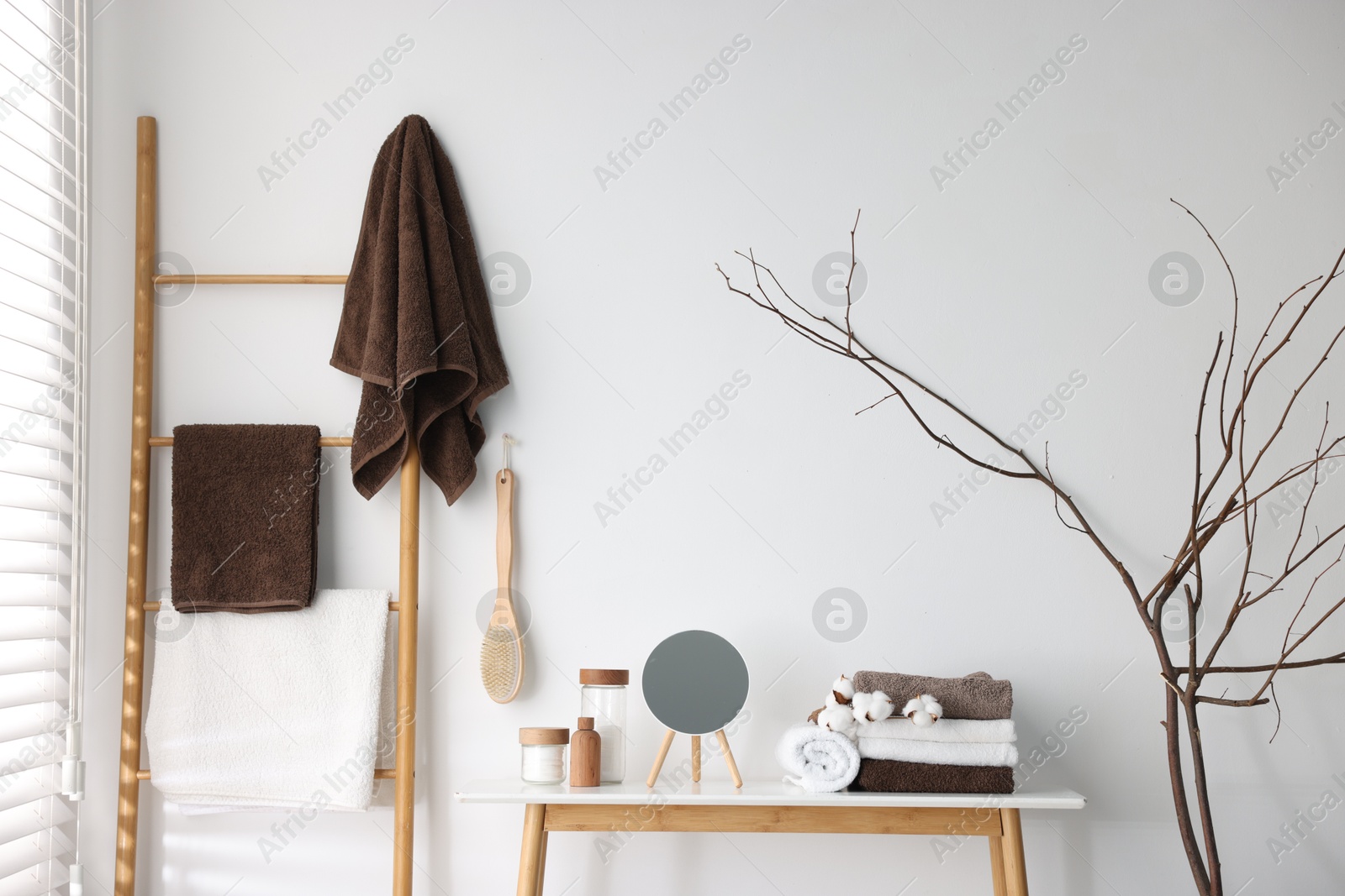 Clean terry towels, bathroom supplies, cotton flowers and mirror indoors Photo of Clean terry towels, bathroom supplies, cotton flowers and mirror indoors