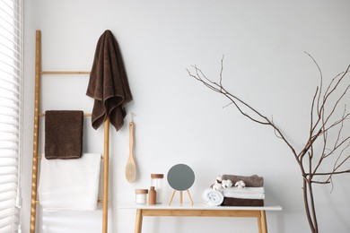 Photo of Clean terry towels, bathroom supplies, cotton flowers and mirror indoors