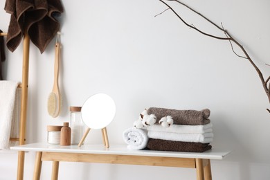 Photo of Clean terry towels, bathroom supplies, cotton flowers and mirror indoors