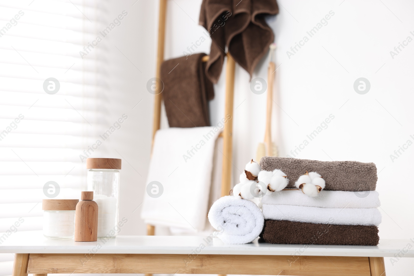 Clean terry towels, bathroom supplies and cotton flowers indoors Photo of Clean terry towels, bathroom supplies and cotton flowers indoors
