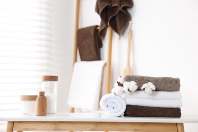 Photo of Clean terry towels, bathroom supplies and cotton flowers indoors