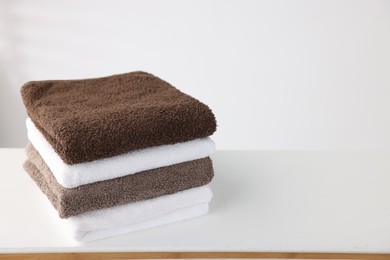 Photo of Stack of clean towels on white table. Space for text