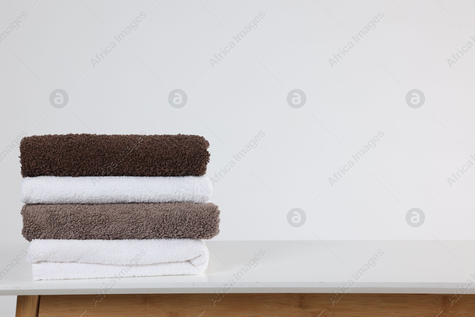 Stack of clean towels on white table, space for text Photo of Stack of clean towels on white table, space for text