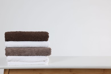 Photo of Stack of clean towels on white table, space for text
