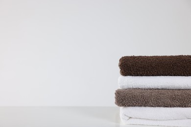 Photo of Stack of clean towels on white table, closeup. Space for text