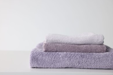 Photo of Stack of clean towels on white table, closeup. Space for text