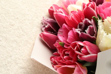Photo of Bouquet of beautiful tulips on white textured table, closeup. Space for text