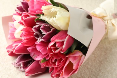 Photo of Bouquet of beautiful tulips on white textured table, closeup