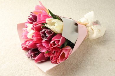 Photo of Bouquet of beautiful tulips on white textured table, closeup