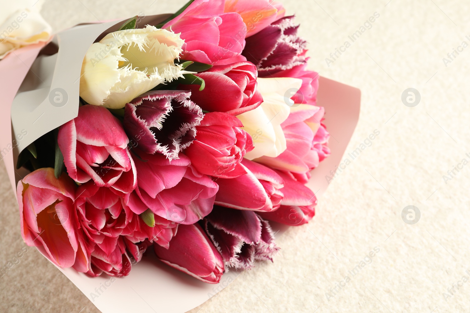 Bouquet of beautiful tulips on white textured table, closeup. Space for text Photo of Bouquet of beautiful tulips on white textured table, closeup. Space for text