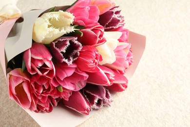 Photo of Bouquet of beautiful tulips on white textured table, closeup. Space for text