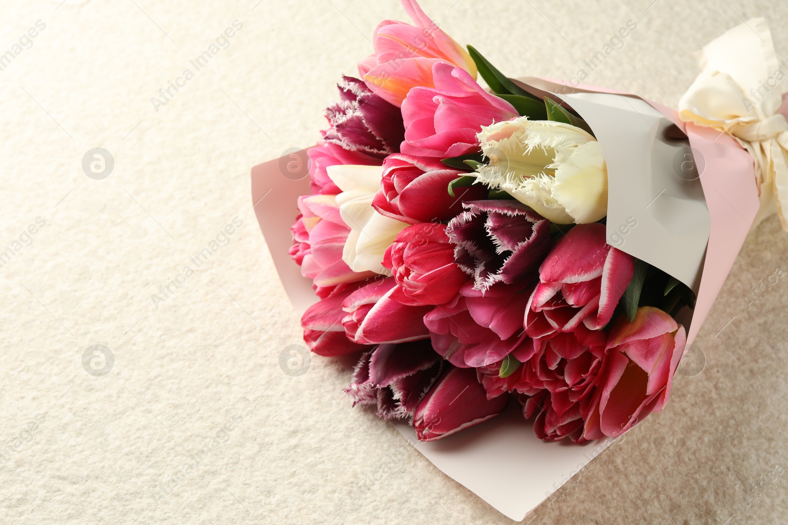 Bouquet of beautiful tulips on white textured table, closeup. Space for text Photo of Bouquet of beautiful tulips on white textured table, closeup. Space for text