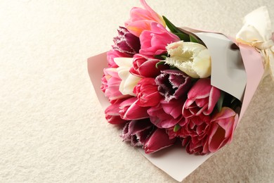 Photo of Bouquet of beautiful tulips on white textured table, closeup. Space for text