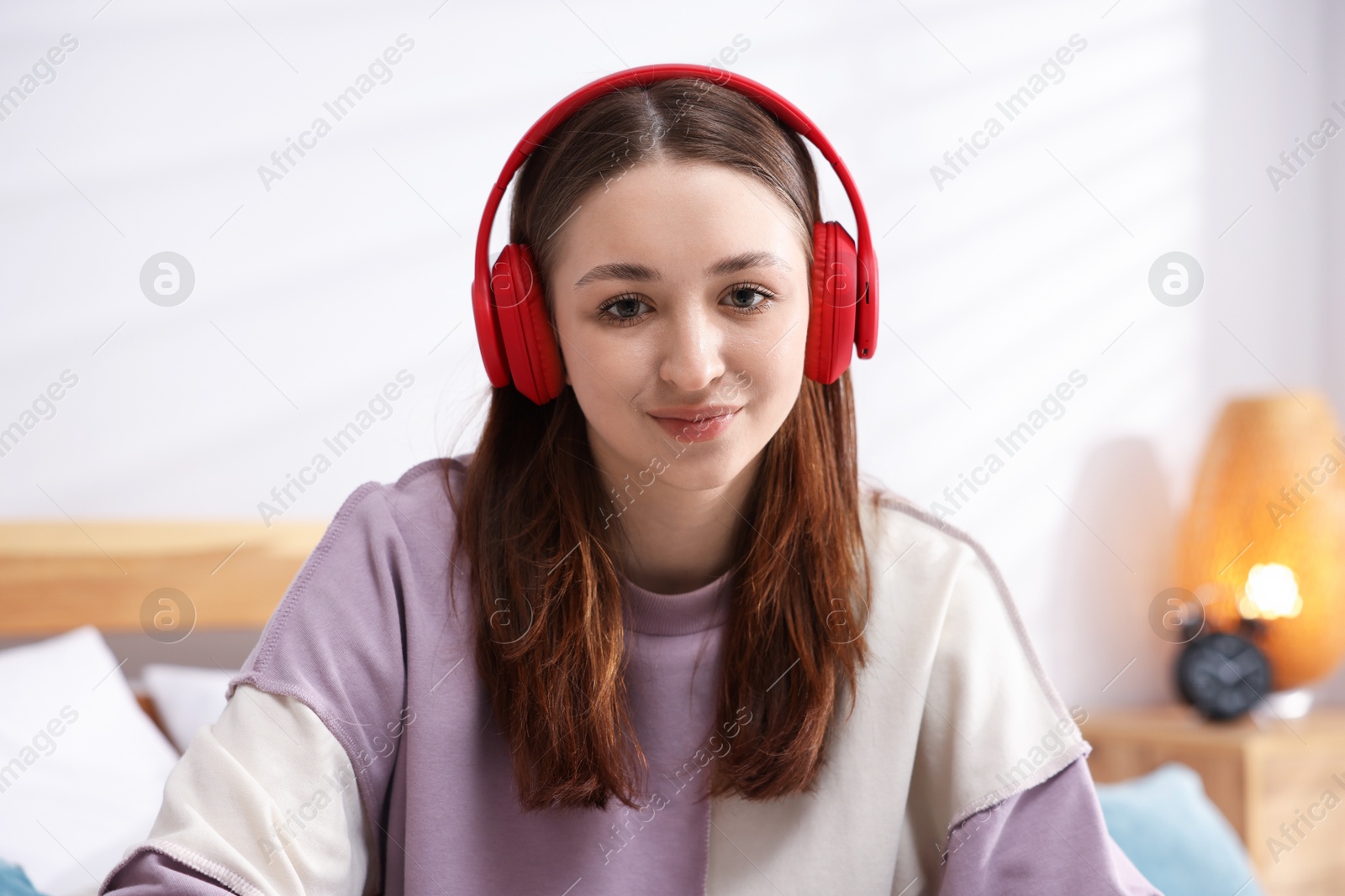 Photo of Teenage girl in headphones listening to music at home