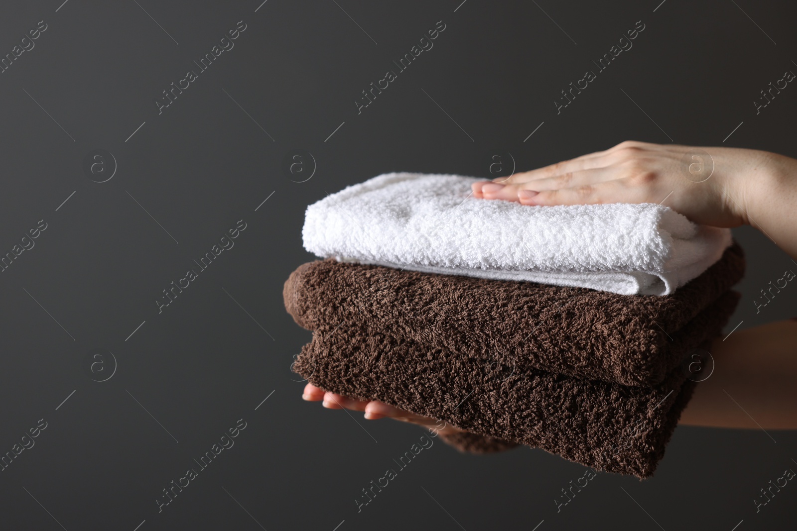 Woman with clean towels on dark grey background, closeup. Space for text Photo of Woman with clean towels on dark grey background, closeup. Space for text