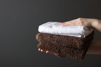 Photo of Woman with clean towels on dark grey background, closeup. Space for text