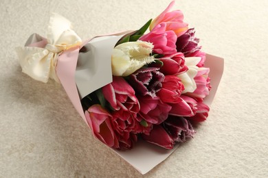 Photo of Bouquet of beautiful tulips on white textured table, closeup