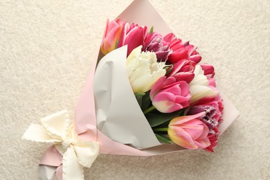 Photo of Bouquet of beautiful tulips on white textured table, top view