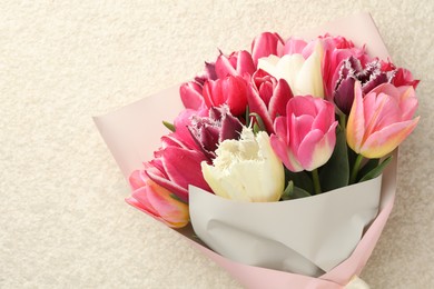 Photo of Bouquet of beautiful tulips on white textured table, top view. Space for text