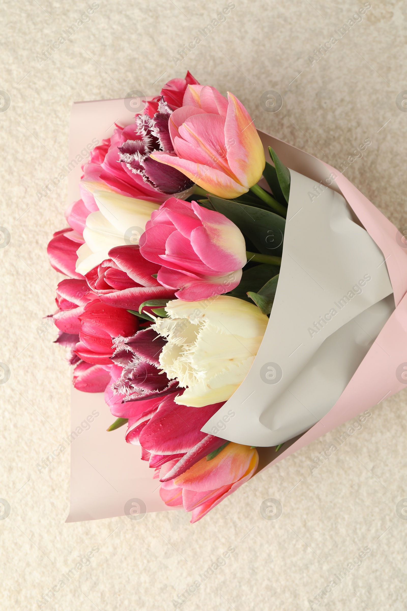 Bouquet of beautiful tulips on white textured table, top view Photo of Bouquet of beautiful tulips on white textured table, top view