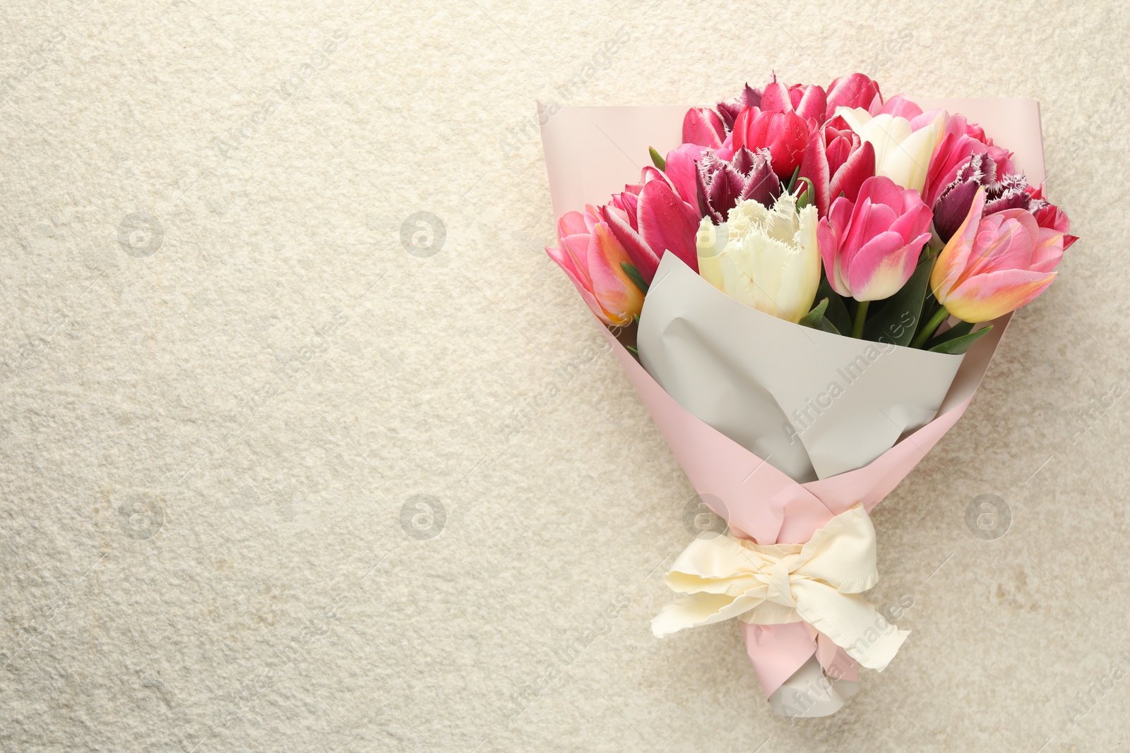 Bouquet of beautiful tulips on white textured table, top view. Space for text Photo of Bouquet of beautiful tulips on white textured table, top view. Space for text