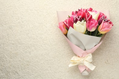 Photo of Bouquet of beautiful tulips on white textured table, top view. Space for text
