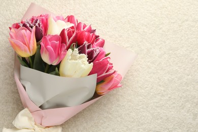 Photo of Bouquet of beautiful tulips on white textured table, top view. Space for text