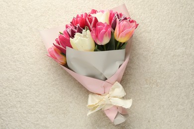 Photo of Bouquet of beautiful tulips on white textured table, top view