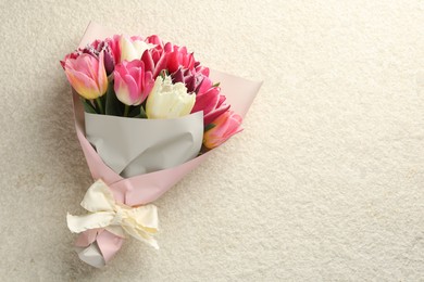 Photo of Bouquet of beautiful tulips on white textured table, top view. Space for text