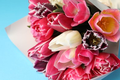 Photo of Bouquet of beautiful tulips on light blue background, closeup