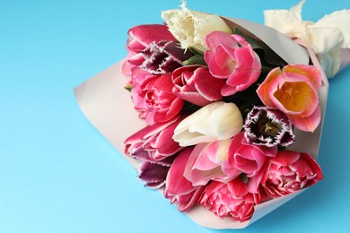 Photo of Bouquet of beautiful tulips on light blue background, closeup. Space for text