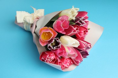 Photo of Bouquet of beautiful tulips on light blue background, closeup