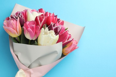Photo of Bouquet of beautiful tulips on light blue background, top view. Space for text