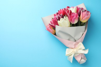 Photo of Bouquet of beautiful tulips on light blue background, top view. Space for text