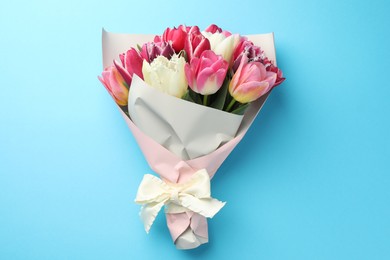 Photo of Bouquet of beautiful tulips on light blue background, top view