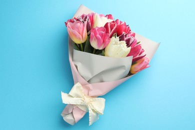 Photo of Bouquet of beautiful tulips on light blue background, top view