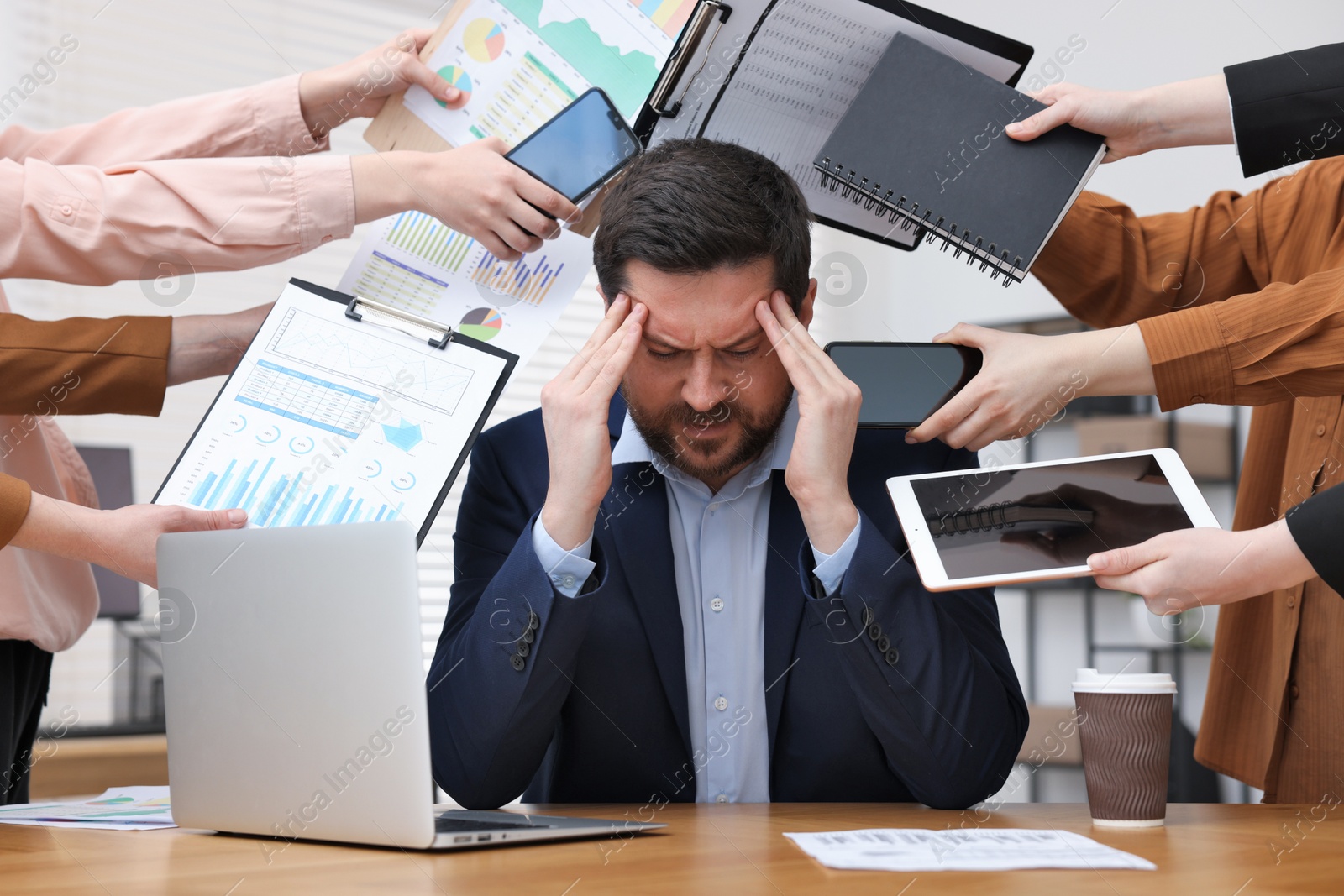 Man overwhelmed by different requests from colleagues at desk in office Photo of Man overwhelmed by different requests from colleagues at desk in office
