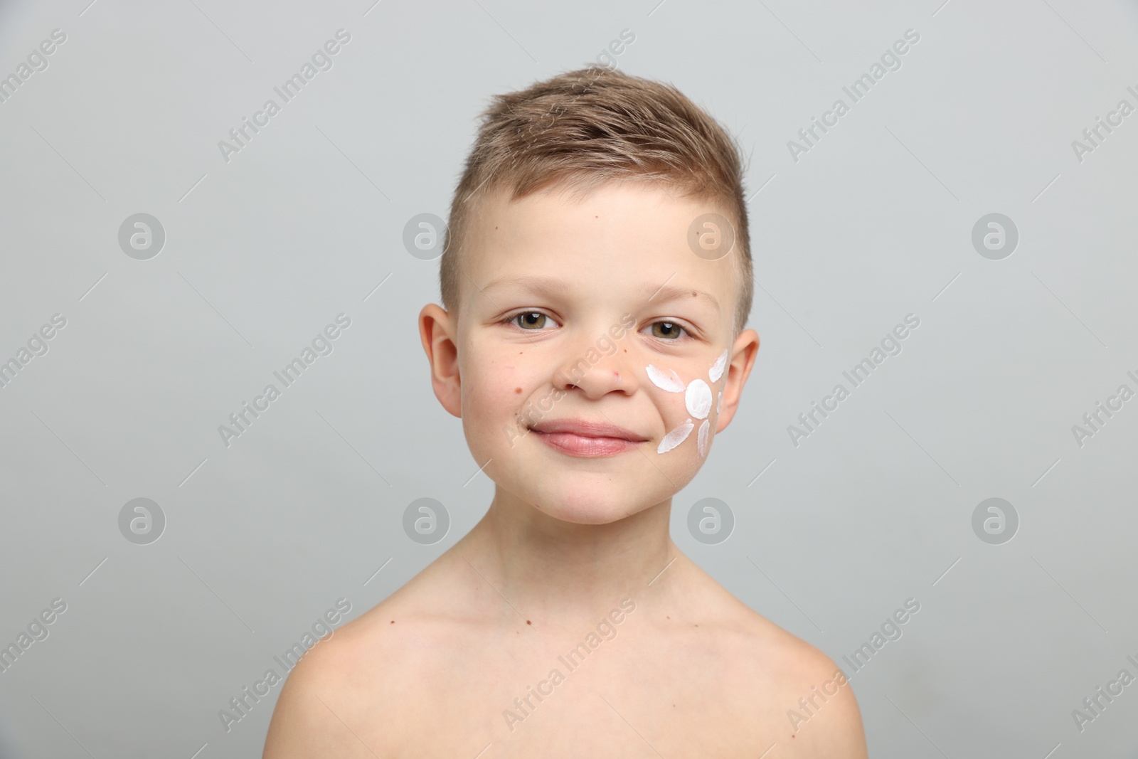 Little boy with sun protection cream on his skin against light grey background Photo of Little boy with sun protection cream on his skin against light grey background