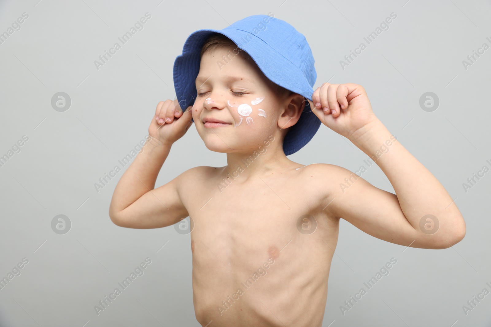 Little boy with sun protection cream on his skin against light grey background Photo of Little boy with sun protection cream on his skin against light grey background