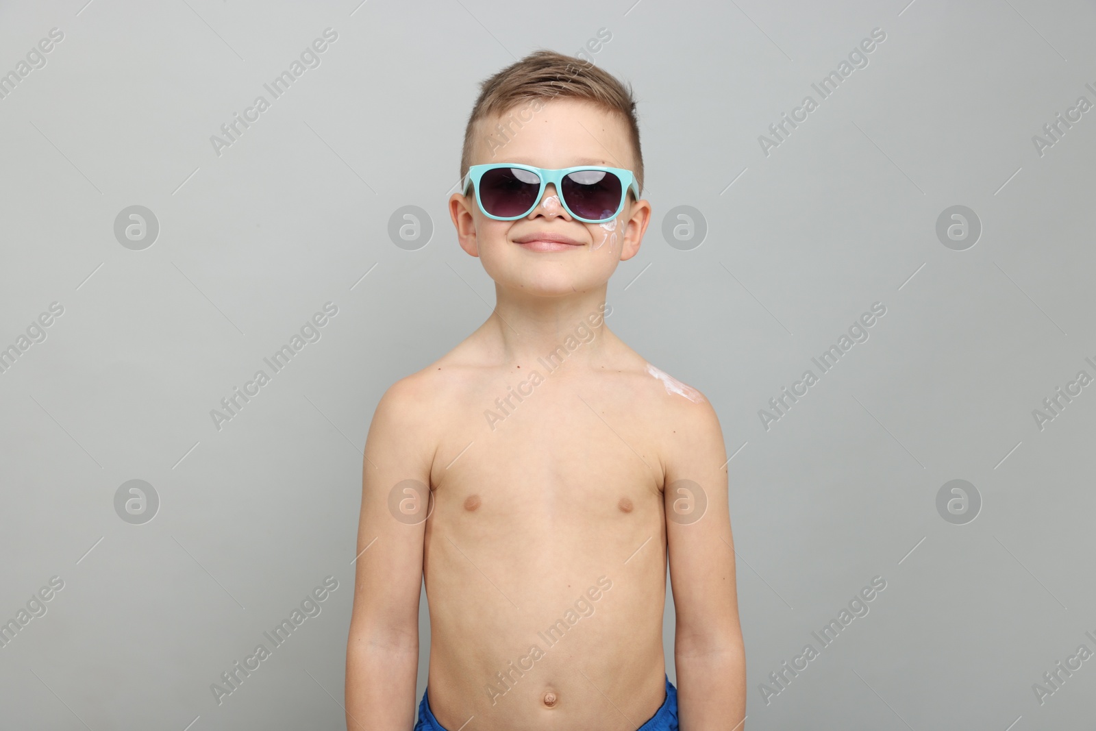 Little boy with sun protection cream on his skin against light grey background Photo of Little boy with sun protection cream on his skin against light grey background