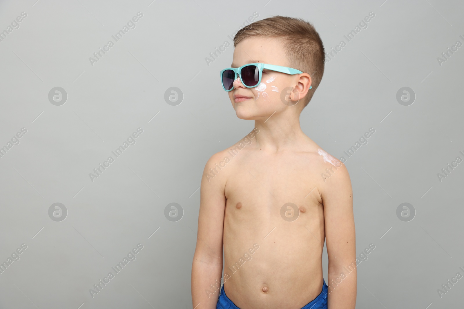 Little boy with sun protection cream on his skin against light grey background, space for text Photo of Little boy with sun protection cream on his skin against light grey background, space for text